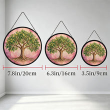 Load image into Gallery viewer, Three Rooted in Abundance Tree of Life glass suncatchers hanging side by side in different sizes, each featuring a green tree and pink background.