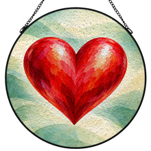 Load image into Gallery viewer, Follow Your Heart red heart stained glass-style suncatcher with a black metal frame and chain, featuring layered sage green and cream artwork.