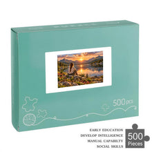 Load image into Gallery viewer, REFLECTIONS 500 piece wooden jigsaw puzzle featuring a woman with a braid sitting on a rock overlooking a glowing mountain lake with wildflowers, ducks, and chipmunks.