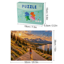 Cargar imagen en el visor de la galería, THE ROAD AHEAD 500 piece wooden jigsaw puzzle featuring a woman walking along a mountain road beside a blue lake with wildflowers, deer, birds, and snow capped peaks.