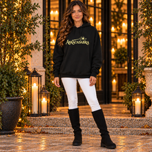 Ladda upp bild till gallerivisning, Woman standing with arms at her sides in black ABRACADABRA graphic hoodie, white skinny jeans, and black knit boots at an evening entrance.