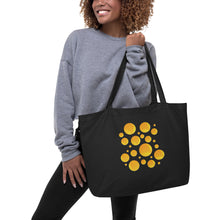 Cargar imagen en el visor de la galería, Model wearing a gray sweater carrying the Solar Pop oversized black organic cotton tote bag featuring original golden yellow and orange abstract circle artwork.