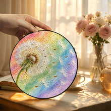 Carica l'immagine nel visualizzatore di Gallery, Hand displaying the Wish Come True dandelion glass suncatcher in a warmly lit room with pink flowers, showcasing its pastel rainbow colors.
