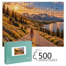 Carica l'immagine nel visualizzatore di Gallery, THE ROAD AHEAD 500 piece wooden jigsaw puzzle featuring a woman walking along a mountain road beside a blue lake with wildflowers, deer, birds, and snow capped peaks.
