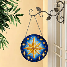 Загрузить изображение в средство просмотра галереи, Written in the Stars glass suncatcher hanging from a decorative metal hook beside a window, displaying golden stars against a rich blue background.

