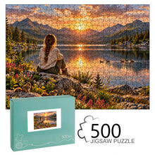 Carica l'immagine nel visualizzatore di Gallery, REFLECTIONS 500 piece wooden jigsaw puzzle featuring a woman with a braid sitting on a rock overlooking a glowing mountain lake with wildflowers, ducks, and chipmunks.
