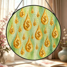 Carica l'immagine nel visualizzatore di Gallery, Close-up of the Make It Rain glass suncatcher displaying detailed golden dollar-sign raindrops and layered green artwork in a warmly styled interior.

