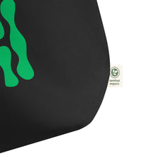 Cargar imagen en el visor de la galería, Close up of the bottom corner of Green Theory oversized black organic cotton tote bag showing vibrant green abstract artwork, fabric texture, and organic cotton label.
