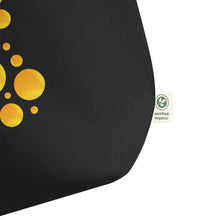 Cargar imagen en el visor de la galería, Close up of the bottom corner of Solar Pop oversized black organic cotton tote bag showing golden yellow abstract circles, premium fabric texture, and organic cotton label.
